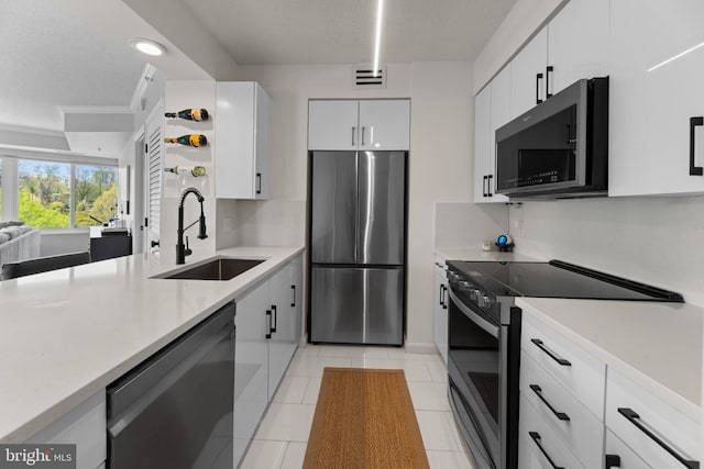 kitchen featuring light countertops, appliances with stainless steel finishes, a sink, and white cabinetry