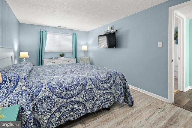13500 Coastal Hwy Unit 201, Ocean City, MD 21842 - bedroom featuring baseboards, a textured ceiling, attic access, visible vents, and wood finished floors