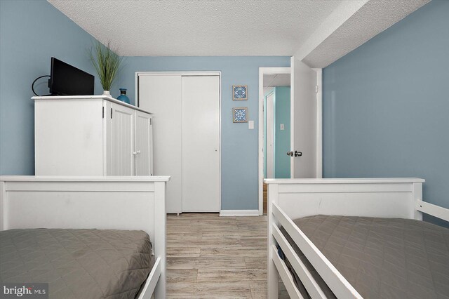 13500 Coastal Hwy Unit 201, Ocean City, MD 21842 - bedroom with a closet, light wood-style flooring, baseboards, and a textured ceiling