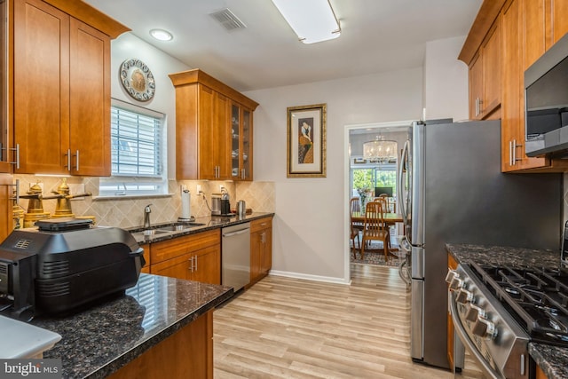 kitchen with appliances with stainless steel finishes, brown cabinets, light wood-style floors, and plenty of natural light