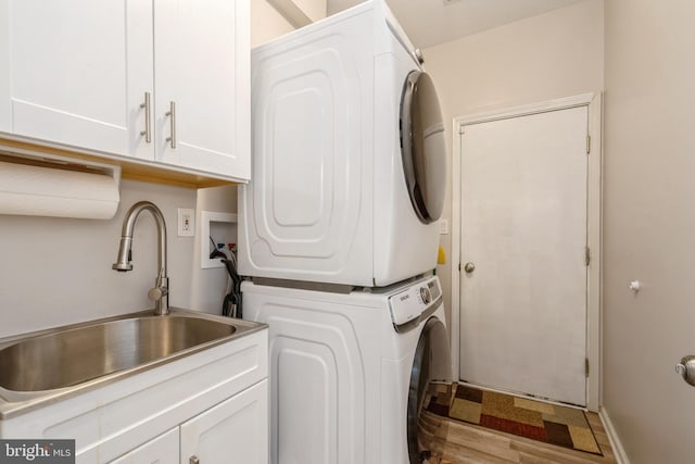 washroom featuring stacked washer and clothes dryer and cabinet space