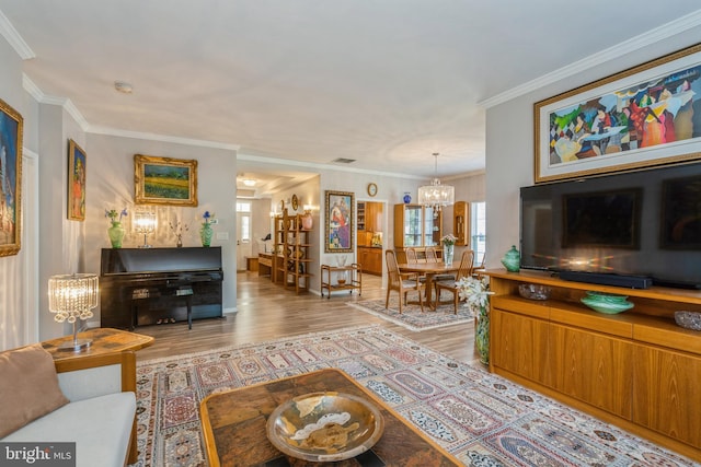 living room featuring plenty of natural light, a chandelier, light wood finished floors, and crown molding
