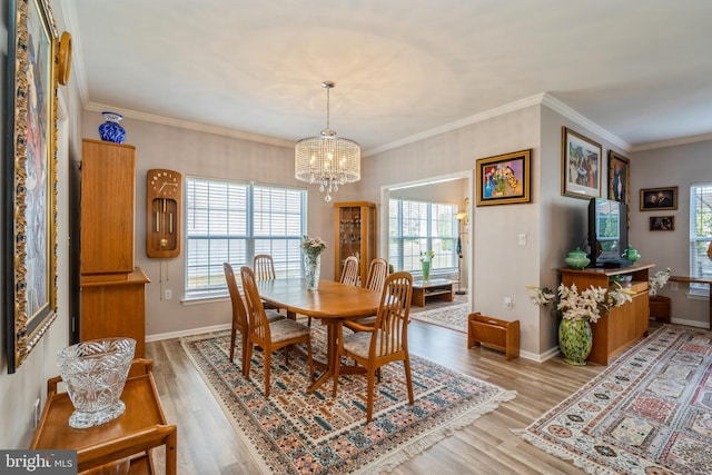 dining room featuring a chandelier, healthy amount of natural light, light wood-style flooring, baseboards, and ornamental molding