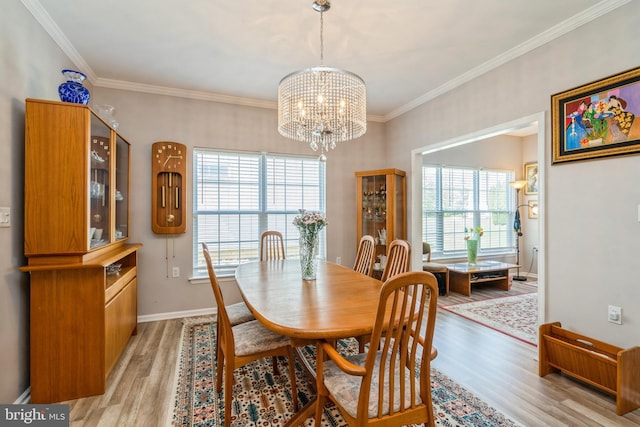 dining room with a chandelier, light wood-type flooring, ornamental molding, and baseboards