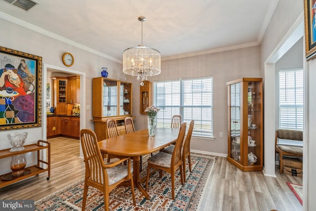 dining area featuring a chandelier, light wood-type flooring, crown molding, and baseboards