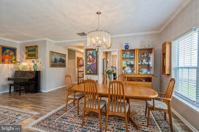 dining room with a chandelier, wood finished floors, baseboards, and ornamental molding
