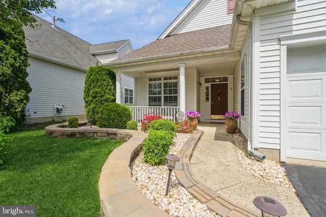 doorway to property with covered porch, roof with shingles, and a lawn