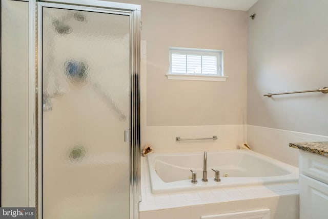 full bath featuring a stall shower, a tub with jets, and vanity