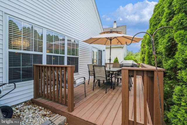 wooden deck with outdoor dining space and area for grilling