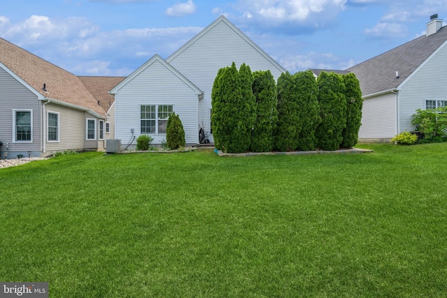 back of property featuring central AC and a lawn