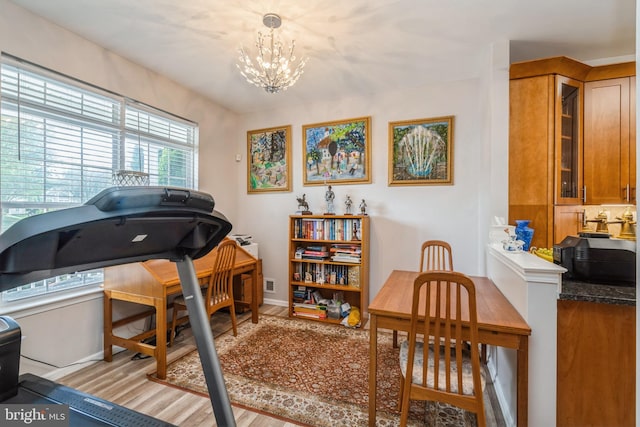 workout room with a chandelier, wood finished floors, and baseboards
