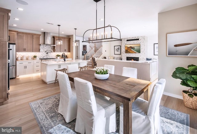 1201 Chesapeake View Dr, Middletown, DE 19709 - dining space with light wood-style flooring, baseboards, an inviting chandelier, stairs, and a fireplace