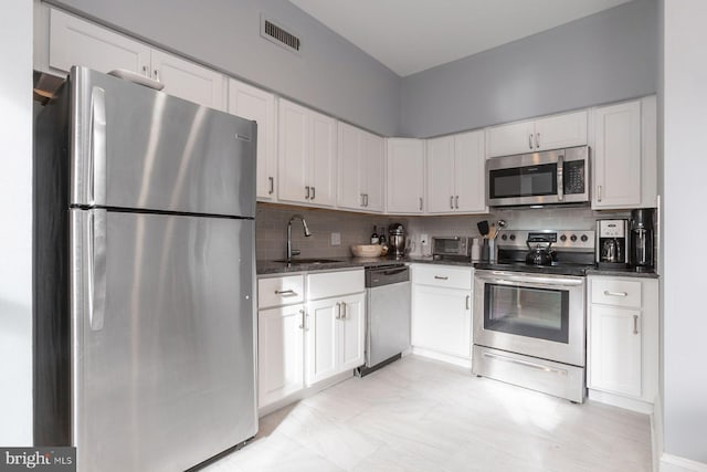 kitchen with white cabinets, a sink, tasteful backsplash, visible vents, and appliances with stainless steel finishes