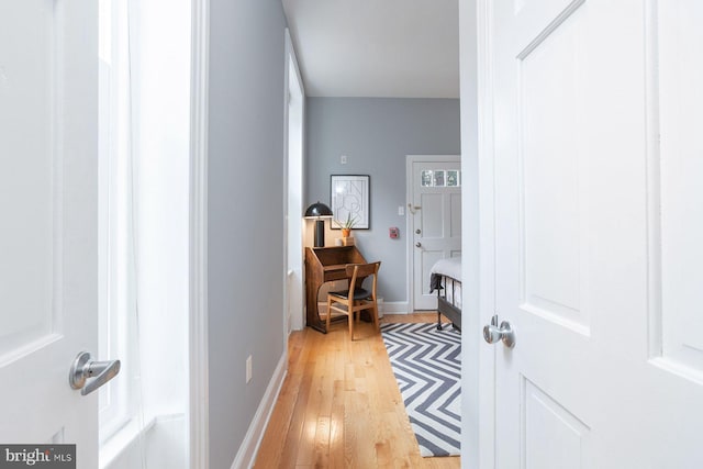 corridor featuring baseboards and light wood-style floors