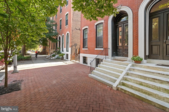 view of exterior entry featuring french doors and brick siding
