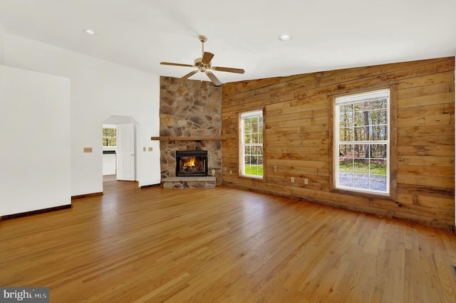 2208 Quarry Rd, Bunker Hill, WV 25413 - unfurnished living room featuring a ceiling fan, a stone fireplace, wood finished floors, and a healthy amount of sunlight