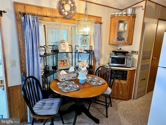 dining room featuring light carpet, a toaster, a notable chandelier, and ornamental molding