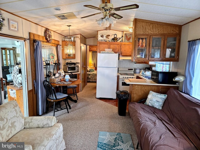 kitchen featuring ornamental molding, white appliances, brown cabinets, lofted ceiling, and carpet