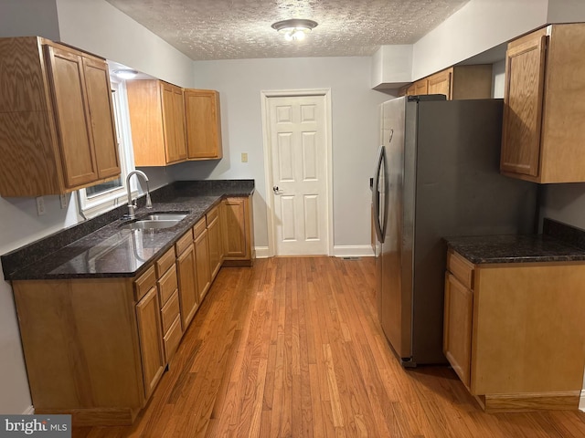 1830 Accokeek Rd W, Accokeek, MD 20607 - kitchen featuring light wood-style floors, stainless steel refrigerator with ice dispenser, dark stone counters, a textured ceiling, and brown cabinets