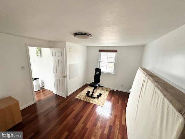 exercise area with dark wood-style floors and baseboards