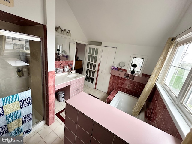 full bathroom with lofted ceiling, a stall shower, tile walls, vanity, and tile patterned flooring
