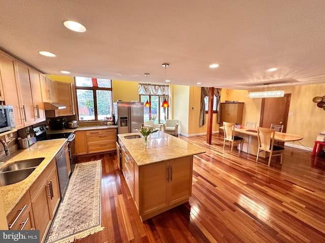 kitchen featuring a sink, stainless steel appliances, under cabinet range hood, recessed lighting, and a center island with sink