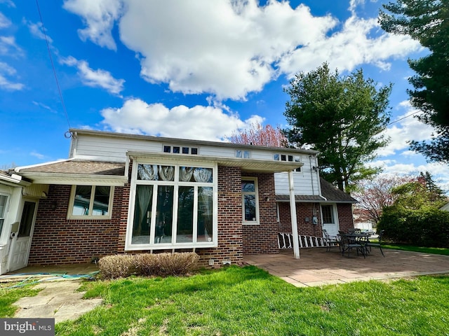 back of house with a patio, a yard, and brick siding