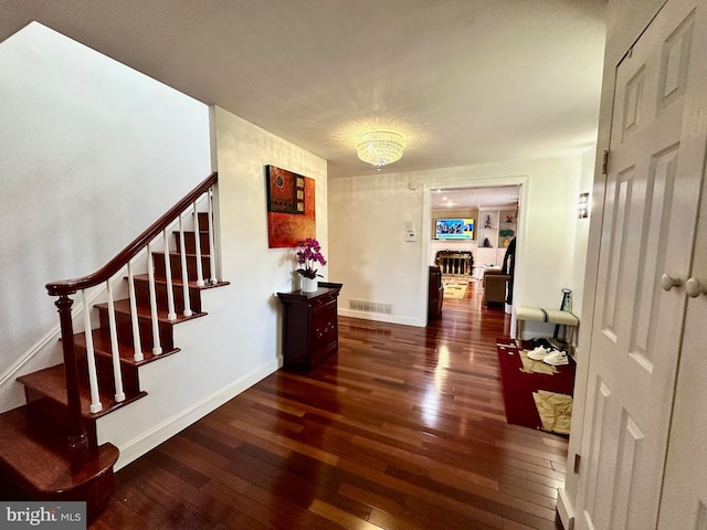 hallway with stairway, visible vents, hardwood / wood-style flooring, and baseboards