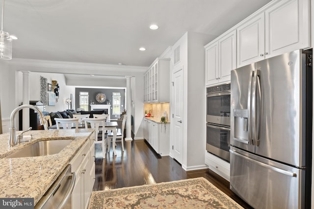 kitchen featuring dark wood-style flooring, a sink, white cabinets, ornamental molding, and stainless steel appliances