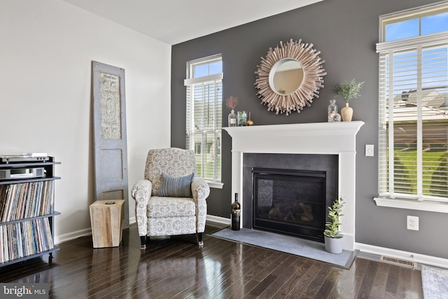 living area with baseboards, visible vents, and wood finished floors