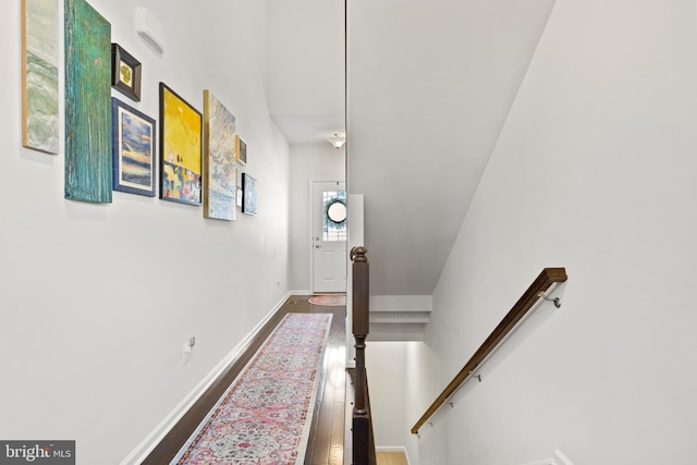 corridor with baseboards, an upstairs landing, and dark wood finished floors