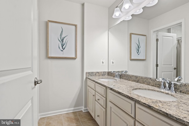 full bathroom with double vanity, baseboards, a sink, and tile patterned flooring