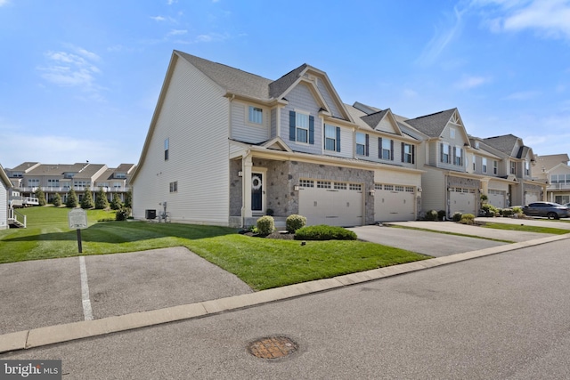 multi unit property with a garage, stone siding, a front yard, concrete driveway, and a residential view