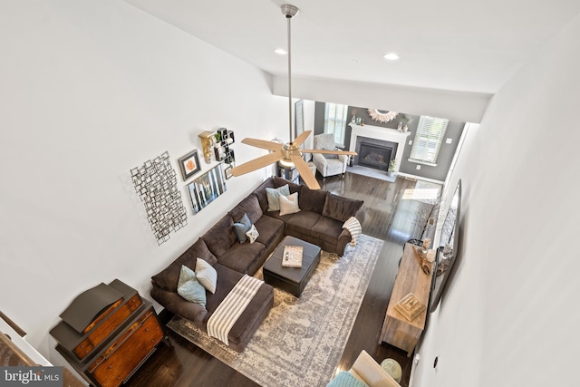 living area featuring a glass covered fireplace, a ceiling fan, recessed lighting, and wood finished floors