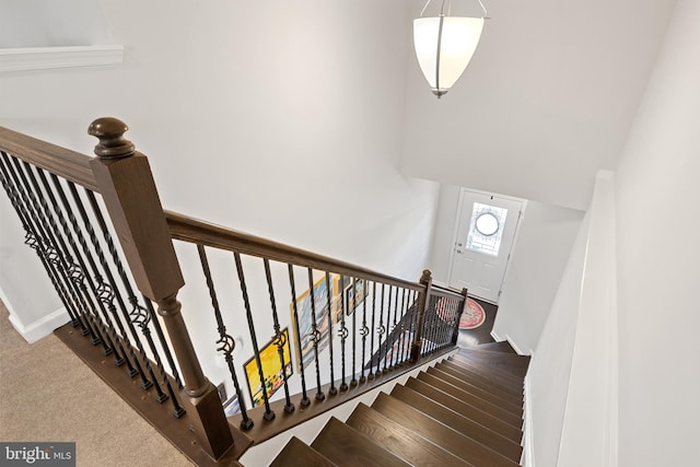 stairs with carpet floors, baseboards, and a towering ceiling