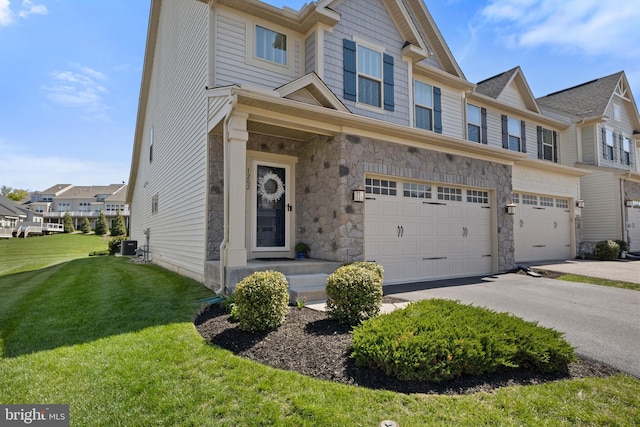 multi unit property featuring a garage, stone siding, driveway, and a front yard