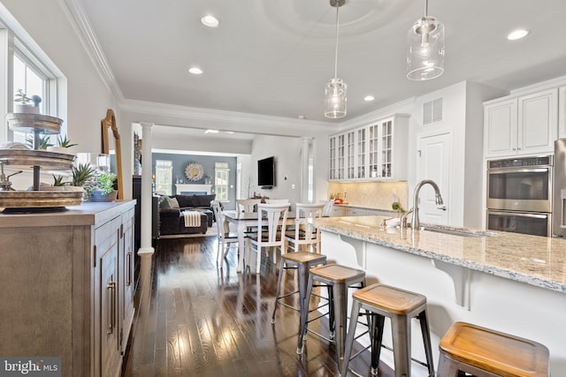kitchen with ornamental molding, dark wood-style floors, a sink, and double oven