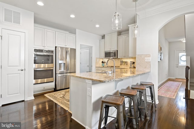 kitchen featuring visible vents, arched walkways, a sink, a peninsula, and stainless steel appliances
