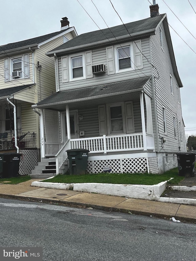 view of front of house featuring a porch, cooling unit, and a chimney