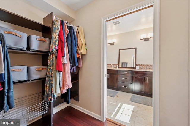 spacious closet with wood finished floors, visible vents, and a sink