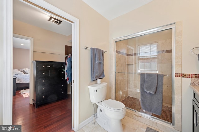 bathroom with toilet, wood finished floors, and a stall shower
