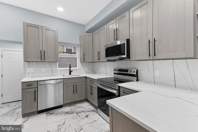 kitchen with light stone counters, recessed lighting, appliances with stainless steel finishes, marble finish floor, and a sink