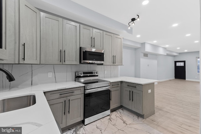 kitchen featuring visible vents, a sink, a peninsula, stainless steel appliances, and gray cabinets