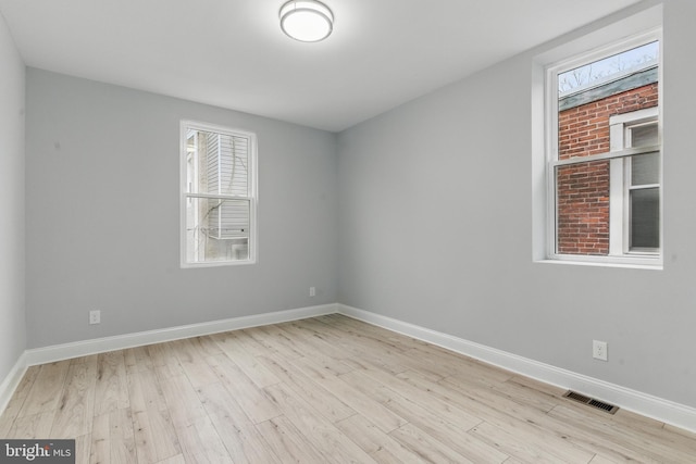 unfurnished room featuring visible vents, baseboards, and wood finished floors
