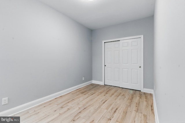 unfurnished bedroom featuring wood finished floors, baseboards, and a closet