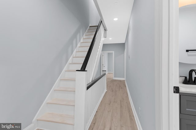 staircase with arched walkways, wood finished floors, baseboards, and recessed lighting