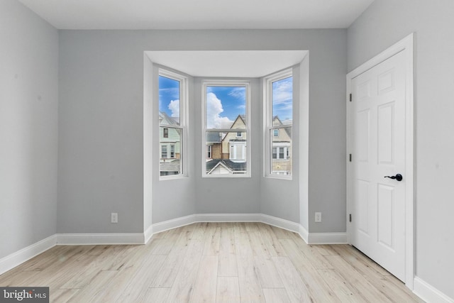 empty room featuring light wood finished floors and baseboards