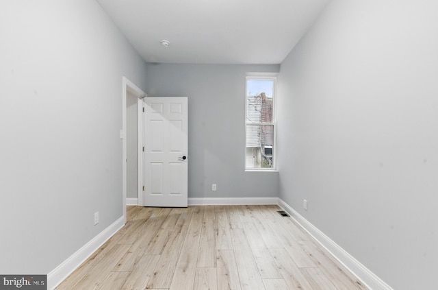 spare room featuring light wood-style flooring, baseboards, and visible vents