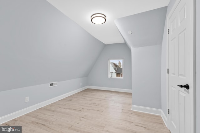 additional living space with visible vents, baseboards, light wood-style floors, and lofted ceiling