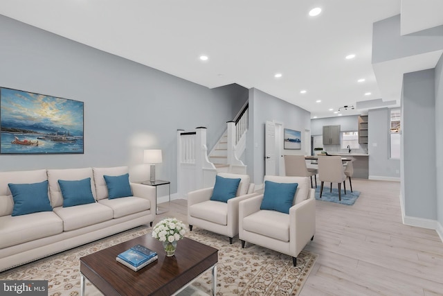 living area featuring stairway, baseboards, light wood-type flooring, and recessed lighting